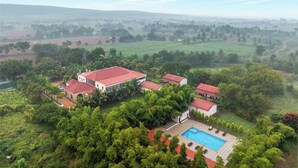 A large house with a swimming pool surrounded by lush greenery and a view of the countryside. - Sterling Banashree Badami  (Badami)