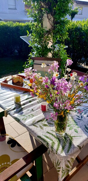 Enjoy a meal al fresco at this outdoor dining area, complete with a beautifully set table and a vase of fresh flowers.