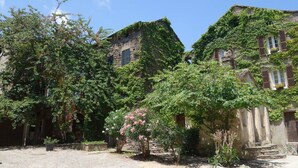 A courtyard with stone walls and ivy-covered buildings.