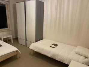 A small, clean room with a single bed, a desk, and a wardrobe.