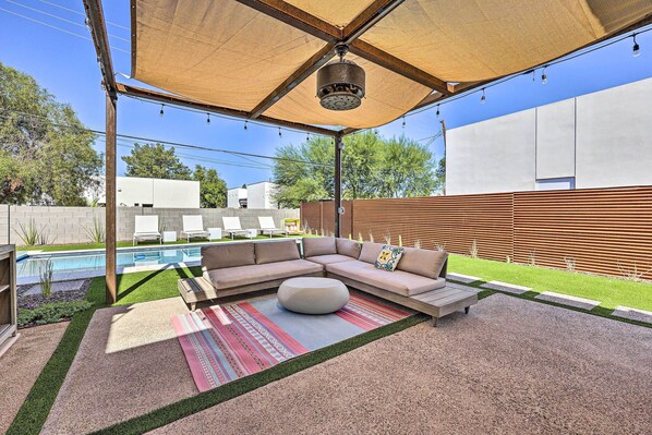 A modern outdoor patio with a sectional sofa, a round ottoman, and a pool in the background. - Backyard Oasis w/ Pool! Family Getaway in Phoenix (Phoenix)
