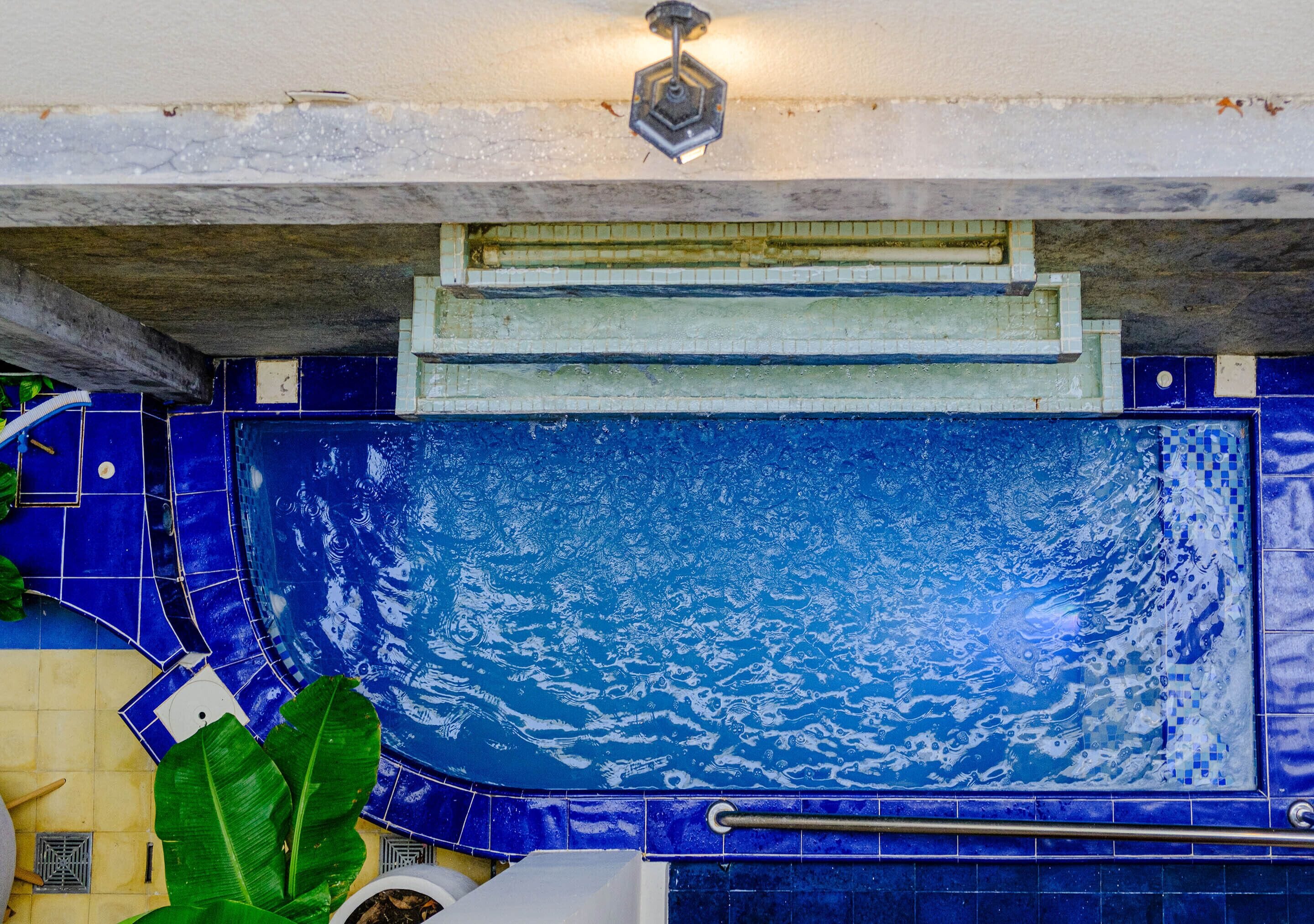 Una piscina con baldosas azules y una barandilla de metal.