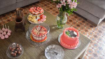 Une table garnie de différents desserts, un vase rempli de fleurs et un sol à motifs.