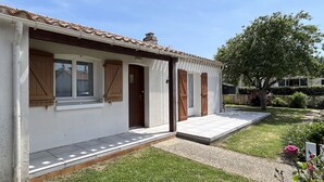 Einbungalow mit Ziegeldach, Eingangstür und kleinem Vorgarten mit Rasen und Blumenbeet.