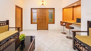 A spacious living area with a wooden door, a glass coffee table, and two sofas. - Roscotel Shara Inn Pondicherry (Puducherry)