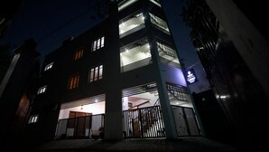 A multi-story building with illuminated windows and balconies, a gated entrance, and a visible sign. - Roscotel Shara Inn Pondicherry (Puducherry)
