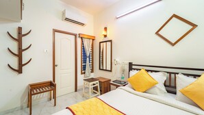 A hotel room with a bed, bedside table, chair, and a mirror on the wall. - Roscotel Shara Inn Pondicherry (Puducherry)
