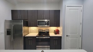 Compact kitchen with a stove, microwave, and refrigerator, offering a convenient cooking space.