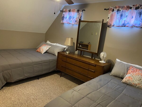 A bedroom with two beds, a dresser, a mirror, and a ceiling fan. - ~~BEAUTIFUL WATERFRONT HOME, SYLVAN BEACH~~ (Blossvale)