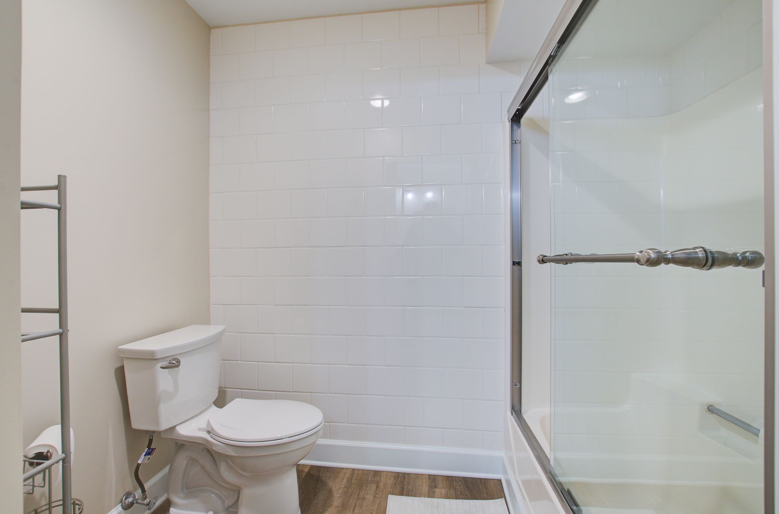 A bathroom with a toilet, a glass shower enclosure, and a tiled wall.