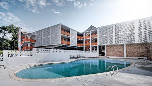 A modern building with a pool, featuring a geometric facade and multiple balconies. - The Admiral Apartments (Jackson)