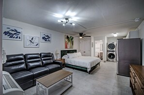 Un dormitorio moderno con cama, sofá, escritorio y ventilador de techo.
