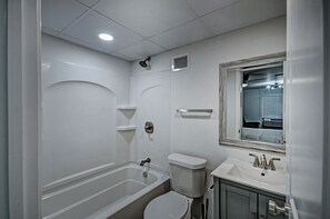 Un baño con bañera, inodoro, lavabo y espejo.