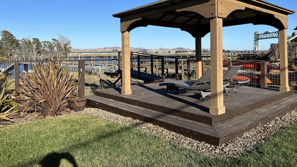 A wooden gazebo with a roof, surrounded by a deck with lounge chairs. - Modern Cottage with Private Dock and large yard on Napa River (Napa)