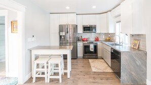 A modern kitchen with white cabinets, stainless steel appliances, and a grey countertop. - Modern Cottage with Private Dock and large yard on Napa River (Napa)