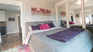 A bedroom with a large bed, a headboard, and a painting on the wall. - Modern Cottage with Private Dock and large yard on Napa River (Napa)