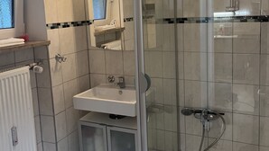 Een moderne badkamer met een glazen douchecabine, een witte wastafel en een spiegel erboven.