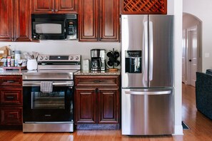Une cuisine moderne équipée d’appareils électroménagers en acier inoxydable, de meubles en bois et d’une machine à café.