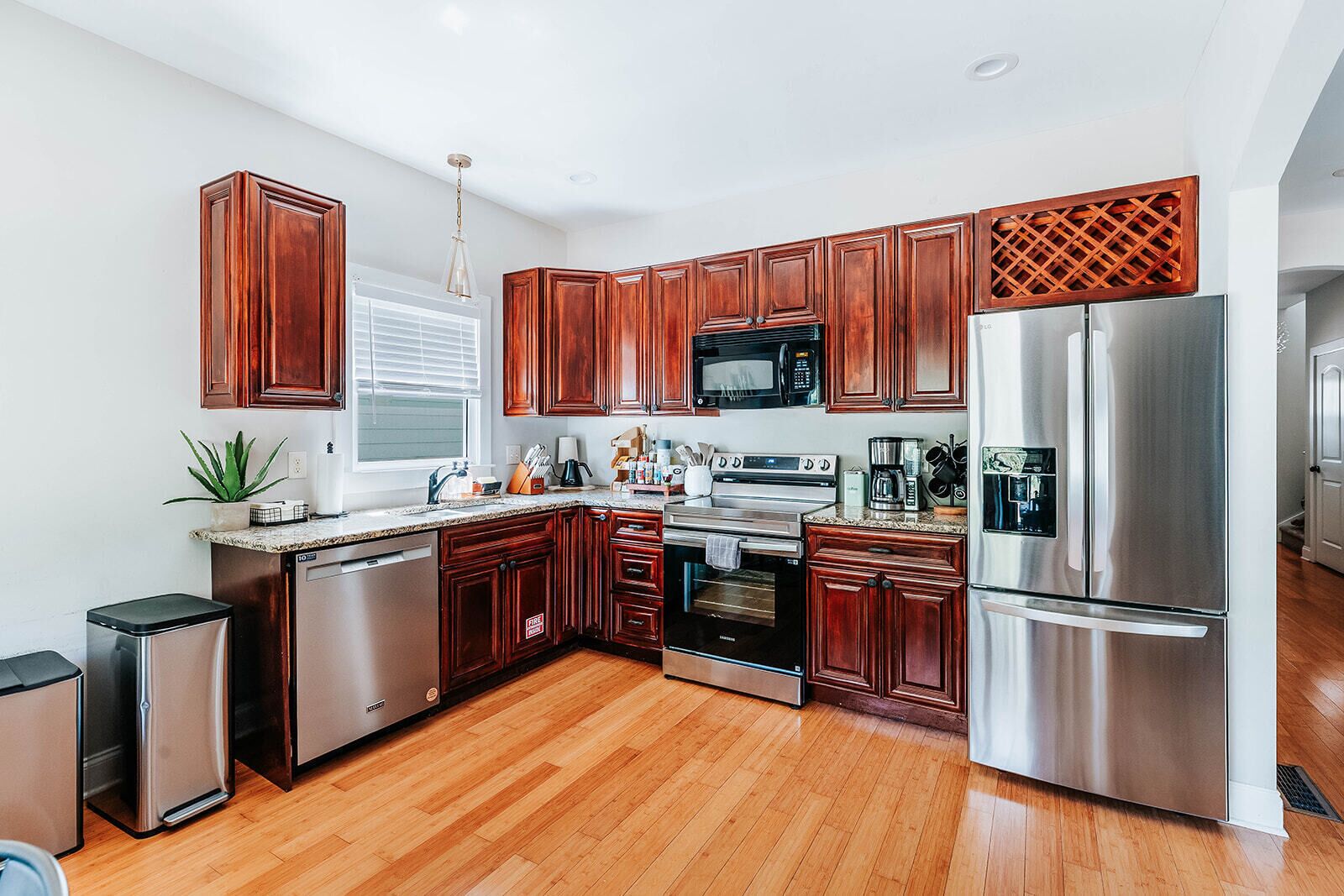 A modern kitchen with wooden cabinets, stainless steel appliances, and a granite countertop.
