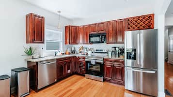 A modern kitchen with wooden cabinets, stainless steel appliances, and a granite countertop.