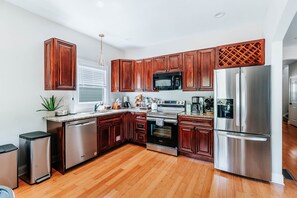 A modern kitchen with wooden cabinets, stainless steel appliances, and a granite countertop. - Master on Main + 2 Living Rooms I Minutes to Downtown, UGA & Sanford I Sleeps 9 (Athens)