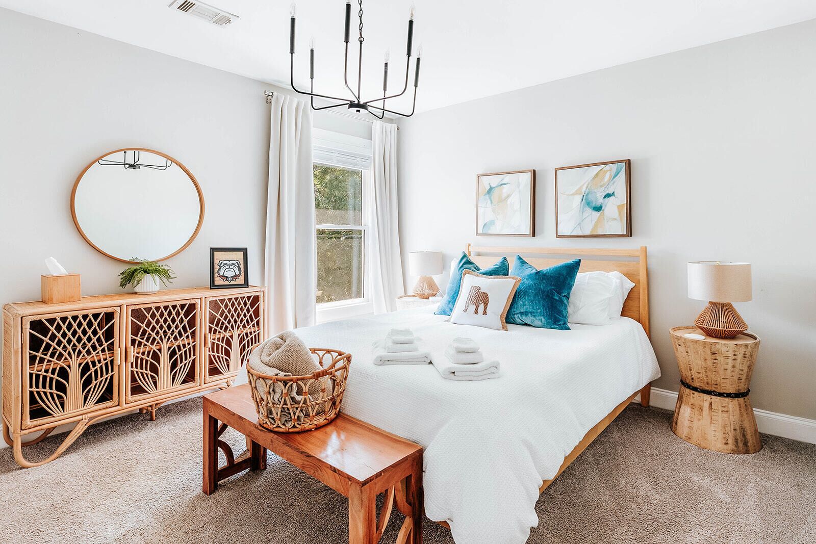 Quarto com cama, mesas de cabeceira, cômoda, espelho e obras de arte na parede.