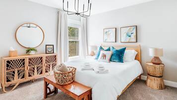 Quarto com cama, mesas de cabeceira, cômoda, espelho e obras de arte na parede.