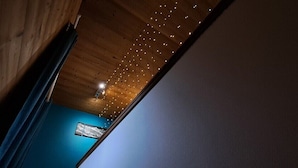 A view of a wooden ceiling with string lights, a blue wall, and a framed picture. - 15-P Chalet, 7BRs, Jacuzzi, Sauna, Prime Loc, Quiet, Cleaning & Linens Incl. (Les Deux Alpes)