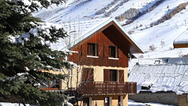 A wooden chalet with a balcony, surrounded by snow-covered trees and a mountainous backdrop. - 15-P Chalet, 7BRs, Jacuzzi, Sauna, Prime Loc, Quiet, Cleaning & Linens Incl. (Les Deux Alpes)
