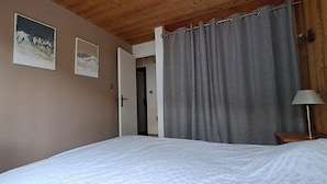 A bedroom with a bed, a door, a curtain, and a lamp. - 15-P Chalet, 7BRs, Jacuzzi, Sauna, Prime Loc, Quiet, Cleaning & Linens Incl. (Les Deux Alpes)