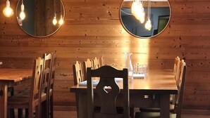 A wooden interior with a round table and chairs, two round mirrors on the wall, and hanging light fixtures. - 15-P Chalet, 7BRs, Jacuzzi, Sauna, Prime Loc, Quiet, Cleaning & Linens Incl. (Les Deux Alpes)