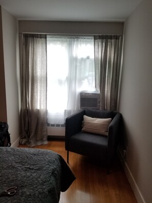 Relax in a cozy space with a single bed, armchair, and sheer curtains.