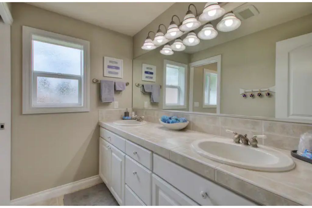 Une salle de bain avec deux lavabos, un grand miroir et un meuble-lavabo avec des tiroirs.