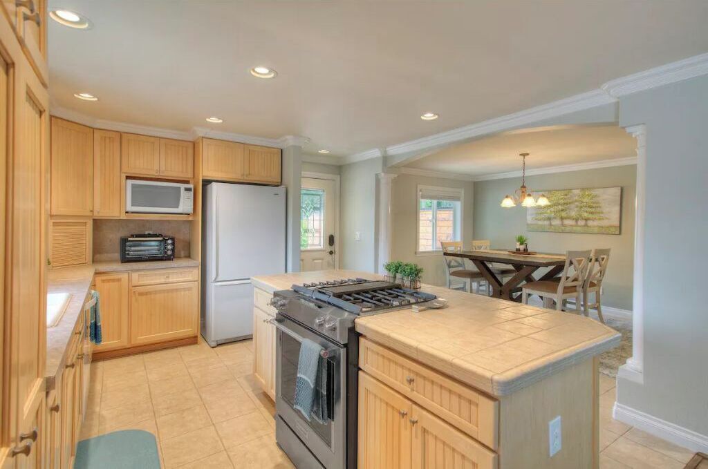 A modern kitchen with wooden cabinets, a built-in microwave, a refrigerator, and a gas stove.