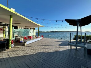 A wooden deck with outdoor seating, a covered area, and a view of the water.