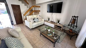 A modern living room with a sofa, coffee table, and a TV mounted on the wall. - Enjoy the beautiful beach villa of Boqueron. Relax in stress-less beach ambiance (Boquerón)