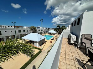 Zona de piscina al terrat amb gandules i ombrelles, envoltada d'edificis moderns.
