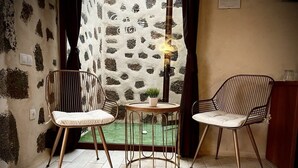 A room with two chairs, a small table, and a view of a garden through a patterned wall.