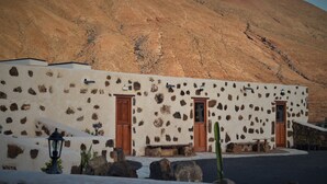 A stone building with two wooden doors and a bench outside.