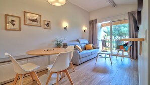 Ein modernes Wohnzimmer mit einem Holzesstisch, weißen Stühlen, einem grauen Sofa und einem Balkon mit einem Sitzplatz.