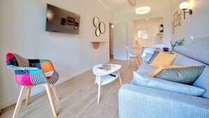 Ein modernes Wohnzimmer mit einem farbenfrohen Sessel, einem grauen Sofa und einem kleinen weißen Tisch.