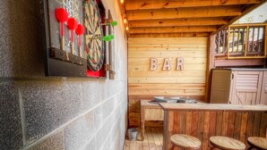 A bar area with a dartboard, stools, and a wooden wall with the word "BAR" displayed. - Cozy lakeside cottage with outdoor haven for fishing, kayaking, and lounging (Ellijay)