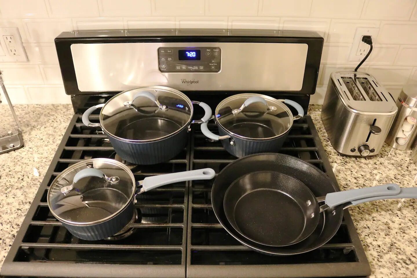 Une cuisine équipée d’une cuisinière Whirlpool, de quatre casseroles et d’un grille-pain.