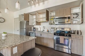 A modern kitchen with granite countertops, stainless steel appliances, and wooden cabinets.