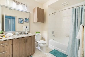 A bathroom with a shower, toilet, sink, and cabinet.