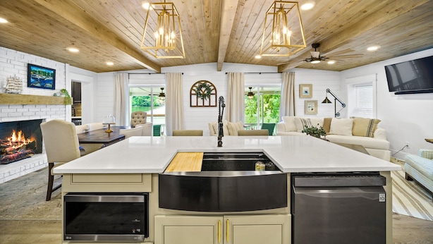 A modern kitchen with a large island, wooden ceiling, pendant lights, and a fireplace. - Canary Cottage Lakehouse on Jackson Lake (Mansfield)
