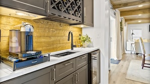 A modern kitchen with dark cabinets, a built-in wine rack, and a coffee machine. - Canary Cottage Lakehouse on Jackson Lake (Mansfield)