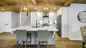 A spacious kitchen with a large island, white cabinetry, and a wooden ceiling. - Canary Cottage Lakehouse on Jackson Lake (Mansfield)