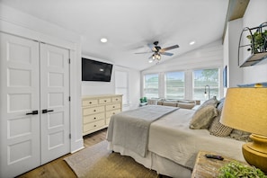 Relax in this serene bedroom with a large bed, bedside table, and mounted television.