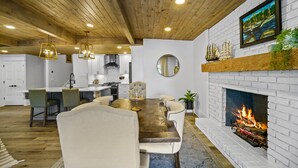 A dining area with a wooden ceiling, white brick fireplace, and a painting above it. - Canary Cottage Lakehouse on Jackson Lake (Mansfield)